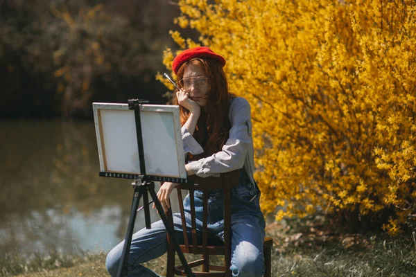 Piękna Ruda Dziewczyna Czerwonym Beretem Siedząca Drewnianym Krześle Jej Dziełami — Zdjęcie stockowe