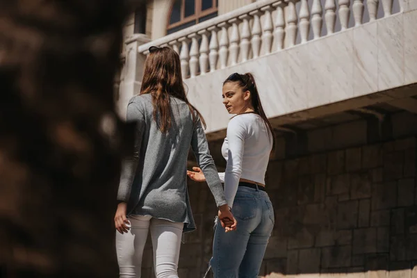Kaksi Kaunista Brunette Tytöt Kävelevät Yhdessä Puhuessaan Kädestä Pitäen — kuvapankkivalokuva