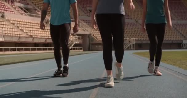 Τρεις Νεαροί Αθλητές Περπατούν Και Χαλαρώνουν Πίστα Αγώνων Στο Γήπεδο — Αρχείο Βίντεο