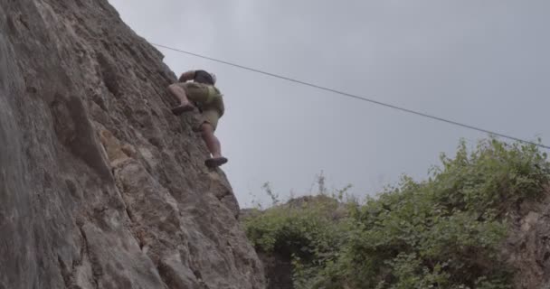 ハンサムとフィットの男は彼がQを登っている間に登山ロープからいくつかの助けを持っている — ストック動画