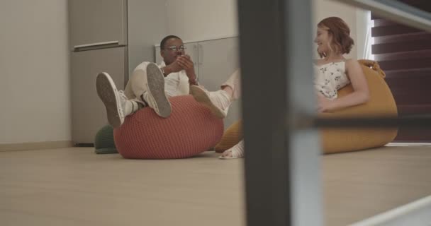 年轻的白人女性和年轻的黑人男性在办公室休息区休息一下 办公室中的积极精神 象征和谐 包容和较少压力 — 图库视频影像