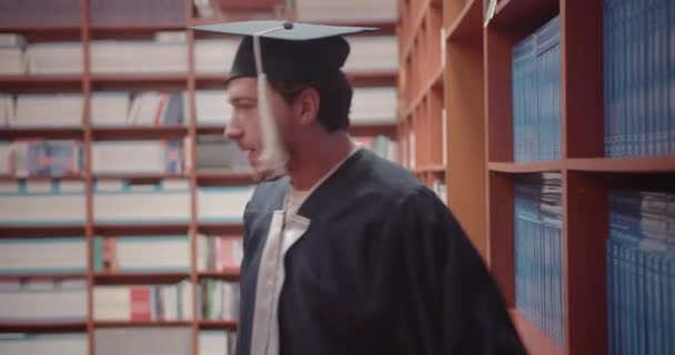 大学の卒業証書を読んで それを達成するために克服しなければならなかったハードルを考えている男性の学生 大学図書館のシーン — ストック動画