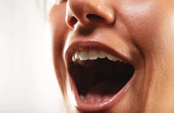 Close up of a girls open mouth  at the studio on a white backround