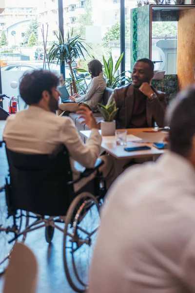 不同的同事在轮椅上倾听残疾男性员工的声音 — 图库照片
