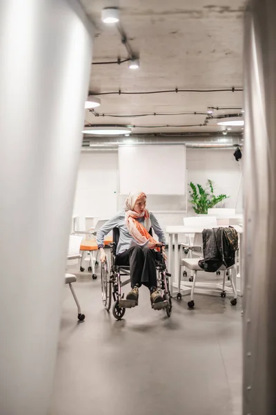 Niepełnosprawna Kobieta Gapiąca Się Coś Podczas Toczenia Wózka Inwalidzkiego Sali — Zdjęcie stockowe