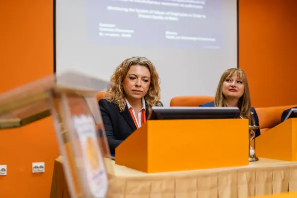 Two female professors listening to their student present a project