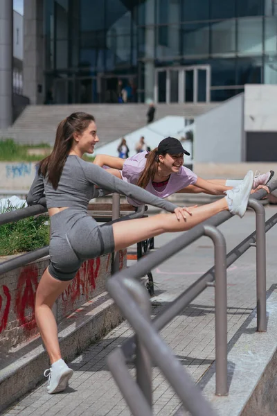Две Красивые Спортивные Девушки Упражняющиеся Ногами Заборе Весело Разговаривают Улыбаются — стоковое фото