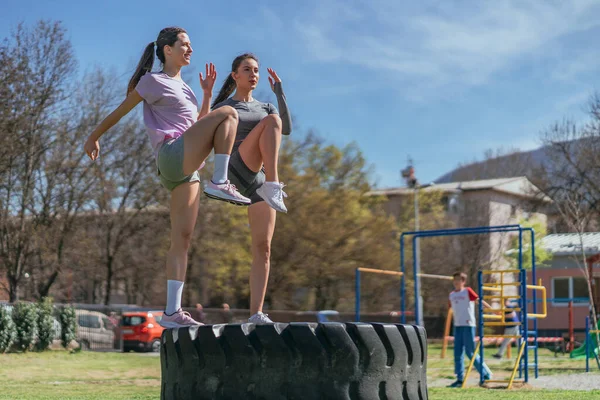 Smiley Sportsgirls Doing Legs Exercices While Standing Big Truck Tire — Stock Photo, Image