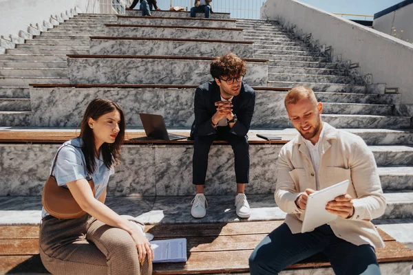 3人のビジネスチームがタブレットの青写真を議論し 街のベンチに座ってリモートで作業 — ストック写真