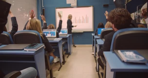 学生举手 教授在智能板上写笔记 并在大学课堂上给学生授课 — 图库视频影像