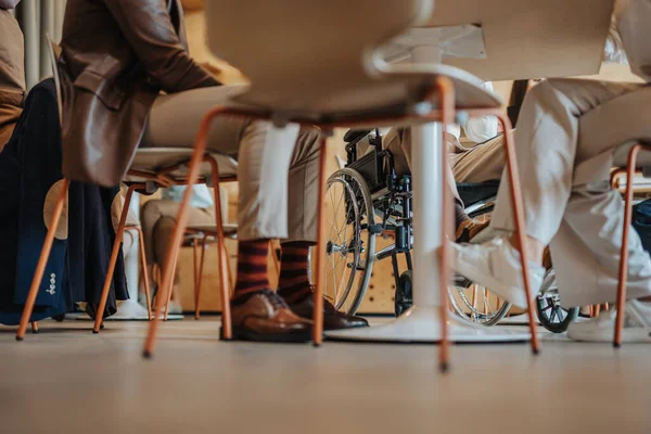 几位同事在一家咖啡店工作 其中一位是残疾人 坐在轮椅上和朋友坐在咖啡店里的家伙 — 图库照片