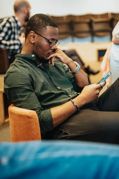 Jonge Afrikaans Amerikaanse Zakenman Zit Comfortabel Naar Zijn Telefoon Kijken — Stockfoto