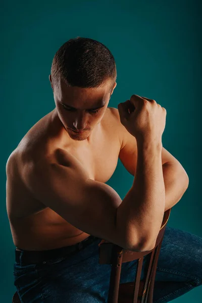 Homem Forte Sentado Cadeira Mostrando Olhando Para Seu Bíceps Posando — Fotografia de Stock