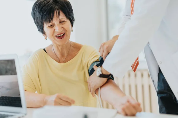 一位心脏病医生对一位老年妇女进行了检查 测量了她的血压 并讨论了她在医院诊所里的健康问题 — 图库照片
