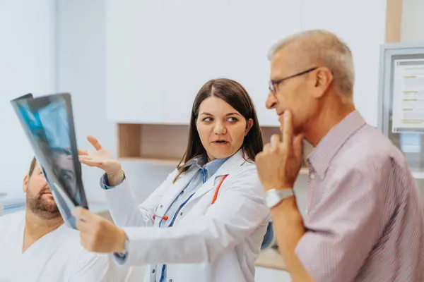 Γιατρός Εξετάζει Προσεκτικά Ακτινογραφικό Φιλμ Συζητώντας Αποτελέσματα Ηλικιωμένους Ασθενείς Εξειδίκευση — Φωτογραφία Αρχείου
