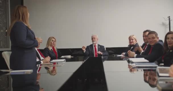 会議室では 上級管理職が重要なビジネス問題について議論しています 彼らはユニフォームの服を着て それぞれ赤いネクタイを着ています ある女性が立ち上がり グループと話し 会話を主導しています カメラトラック — ストック動画