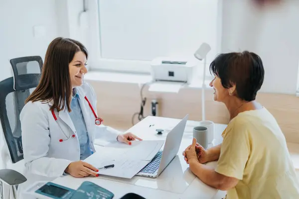 Experienced doctor analyzing test results and discussing diagnosis with elderly patient in medical office. Careful communication provides satisfied and positive experience for patient.