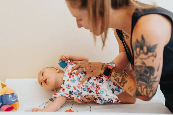 Madre Joven Tatuada Poniendo Bebé Una Cama Consultorio Médico Preparándolo —  Fotos de Stock