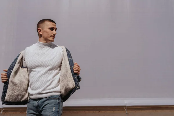 Schöner Junger Mann Posiert Mit Jeansjacke Vor Der Grauen Wand — Stockfoto