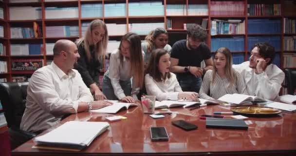 Bustling Universitetsbibliotek Grupp Olika College Studenter Samlas Runt Ett Bord — Stockvideo