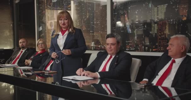 会議室で会議室でビジネス問題を議論するシニアマネージャーは 赤いネクタイで均一な衣装を着て 女性が立って話す — ストック動画