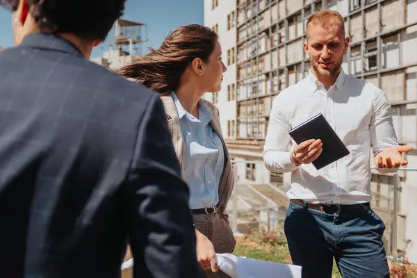 stock image Excited male architect explaining interesting project to his teammates during meeting out in the city, on a sunny day