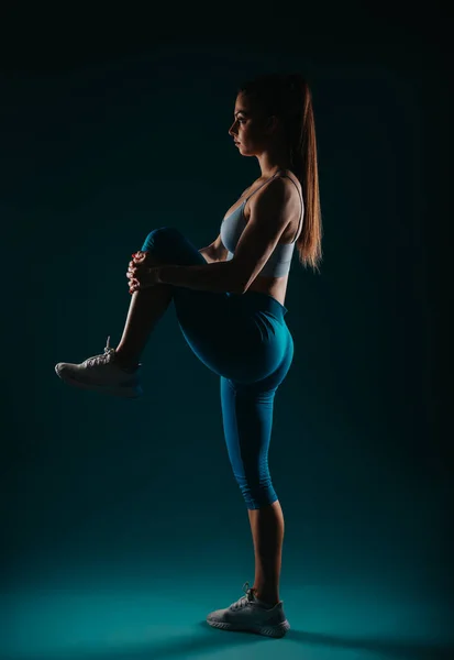 健康的女孩在黑暗的工作室里锻炼 力量和决心 激发健身动机 — 图库照片