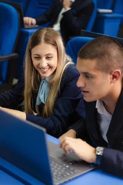 Male and female student working together on a laptop in class