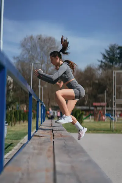 スポーツジョギルス 脚の練習 彼らは公園のベンチでジャンプしています サイドビューショット — ストック写真