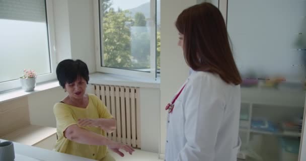 70代の女性患者が彼女の首と腕の痛みを専門医に説明しています — ストック動画
