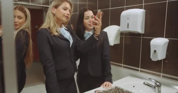 髪を修理しながらセルフィーをとり 大学トイレのトイレでメイクをする女性学生 — ストック動画