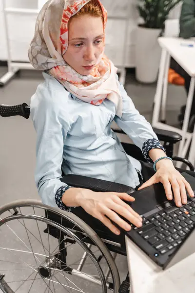 現代のコワーキングスペースでラップトップに取り組む車椅子フリーランサーのハンディキャップ女性 — ストック写真