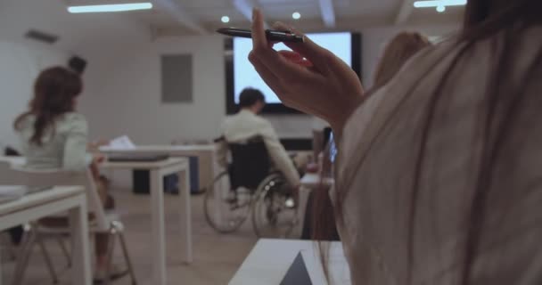 在一次工作研讨会上 一个特写镜头捕捉到一个女孩在工作时正在转笔 在参加者中 有一名坐在轮椅上的残疾雇员被安排在小组的前面 — 图库视频影像