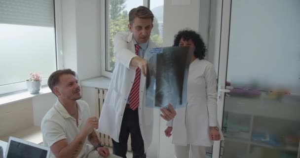 Два Специалиста Мужчина Женщина Обсуждают Объясняют Результаты Рентгена Своему Молодому — стоковое видео