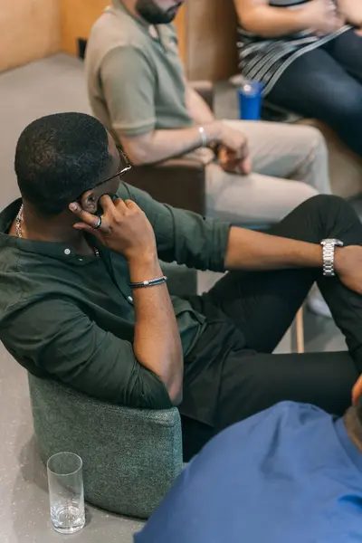 アフリカ系アメリカ人男性が座って会議に出席しながら他の人と話す — ストック写真