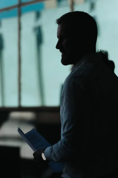 Silhouet Van Een Man Met Papierwerk Lopen Naar Iets Kijken — Stockfoto