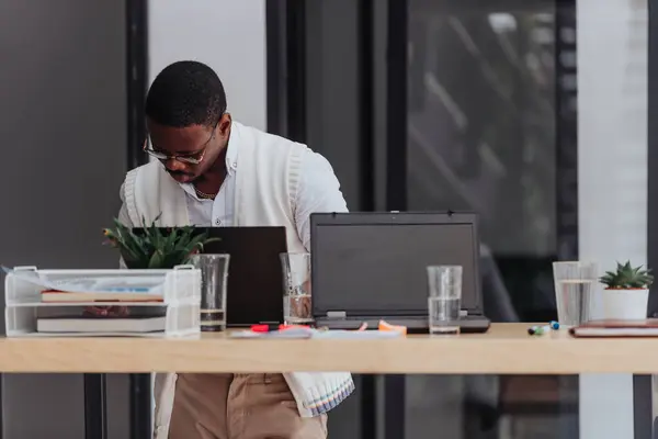 Black male person doing paperwork and analyzing stats at the office.