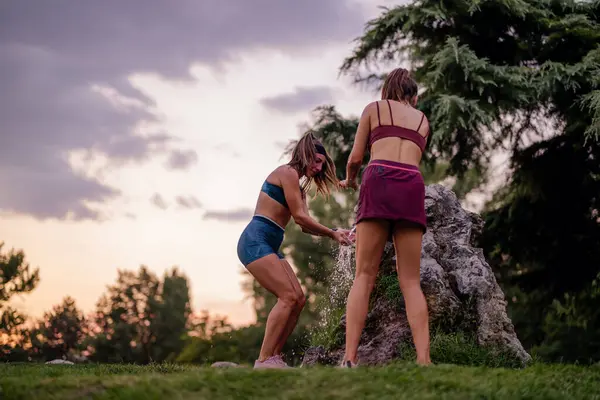 Active, attractive women with fit bodies enjoy a fun evening outdoors, playing and splashing water. Its a joyful display of strength and flexibility in a healthy lifestyle.
