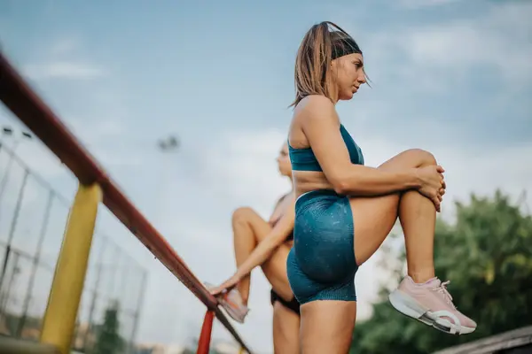 屋外で運動服を着用するアクティブな女性 彼らは彼らの腕と脚を伸ばし 美しい公園でのトレーニングの準備をする フィット感と筋肉 彼らは健康的なライフスタイルを刺激します — ストック写真