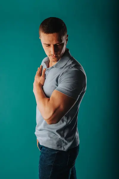Appealing and well-built man standing in a green room and flexing his muscles