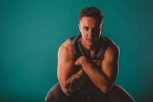 Selbstbewusster Fitter Mann Der Vor Türkisfarbenem Hintergrund Die Muskeln Spielen — Stockfoto