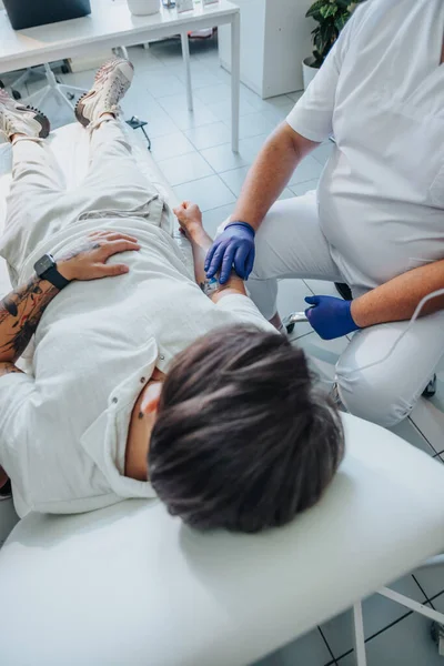 医師の注射を受けるベッドに横たわる若い男性患者 — ストック写真