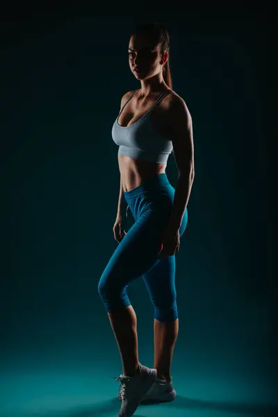 スタジオで筋肉の体格を示すフィットな女性 強さとモチベーションを示すシルエット 彼女はボディトランスフォーメーションとフィットネスの目標のインスピレーションとして役立ちます — ストック写真