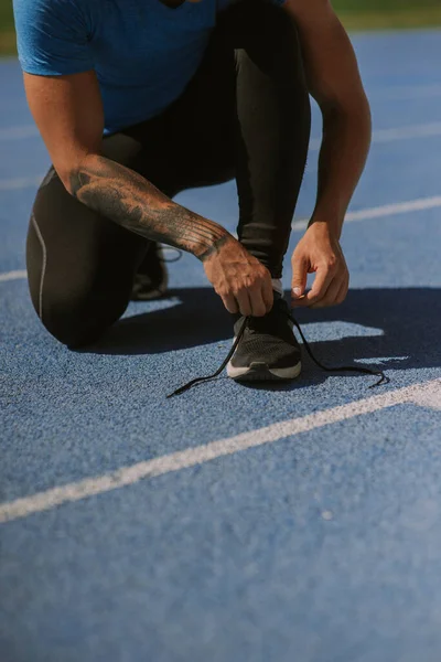 一个肌肉发达的男子运动员在慢跑前正在系鞋带 — 图库照片