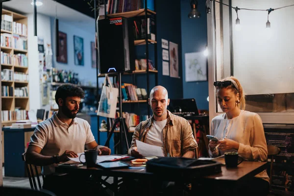 ビジネスパートナーは カジュアルな夜のカフェの設定でコーヒーに関するプロジェクト文書を議論します 成功したチームワークと有益なパートナーシップのための効果的なコミュニケーション — ストック写真