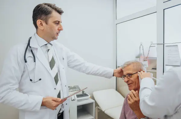 この医療現場では 経験豊富な医師が高齢者に包括的なケアを提供しています 彼らは目 喉の検査を行い 正確な診断と治療を確保する — ストック写真