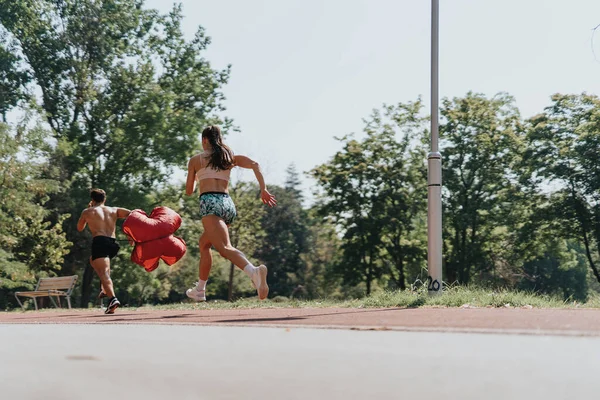 活跃的白种人夫妇在阳光灿烂的公园里跑步 享受户外运动训练 带着降落伞 他们一起冲刺 以获得更好的体形和健康的结果 — 图库照片