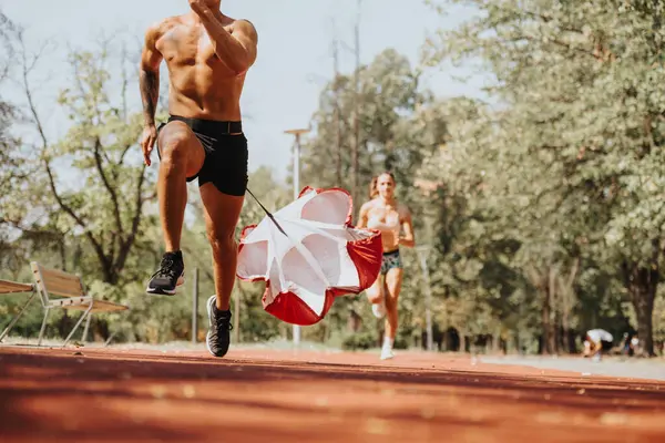 活跃的高加索夫妇一起在公园里跑步 带着降落伞在户外训练 以获得更好的体形和力量 他们健康的身体展示了他们锻炼的积极成果 — 图库照片