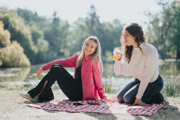 2人の若い女性は 自然に囲まれた晴れた市立公園で気取らない会話をしています 彼らはポジティブさと幸せを放射し 一緒に時間を楽しんでいる — ストック写真