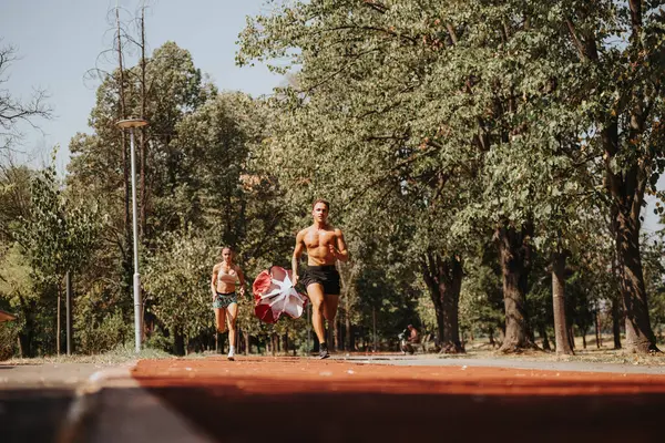 在公园里积极参加户外运动的夫妇 他们冲刺 带着降落伞跑 一起训练 在竞争的激励下 他们努力使自己的身体更健康 肌肉更强壮 — 图库照片